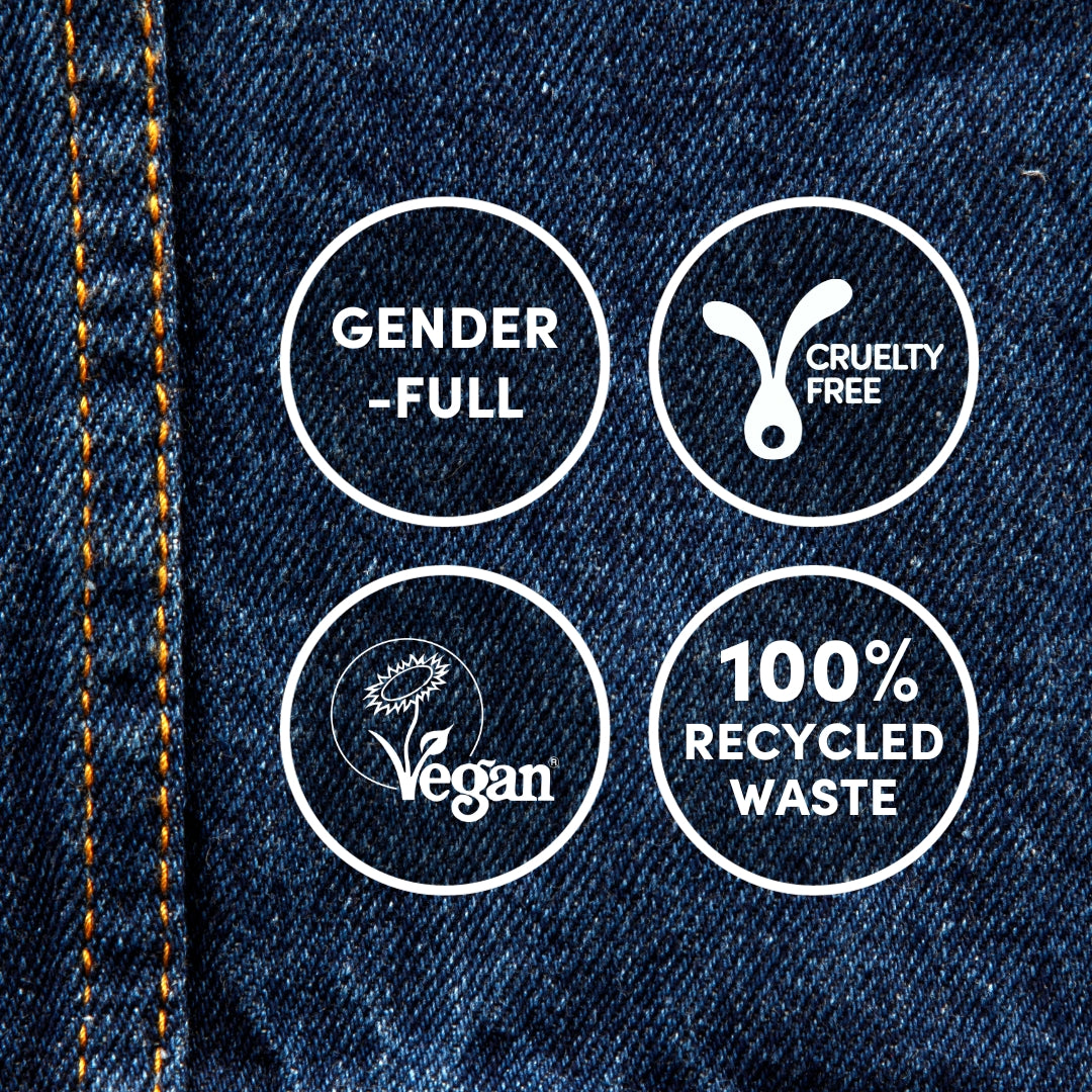 A close-up of #3.8 Dark Denim Permanent Hair Dye by Oiamiga with four circular icons. The icons contain the following texts: "GENDER-FULL," "CRUELTY FREE" with a rabbit symbol, "VEGAN" with a leaf and sun symbol, and "100% RECYCLED WASTE." Cool orange stitching runs along the left edge.